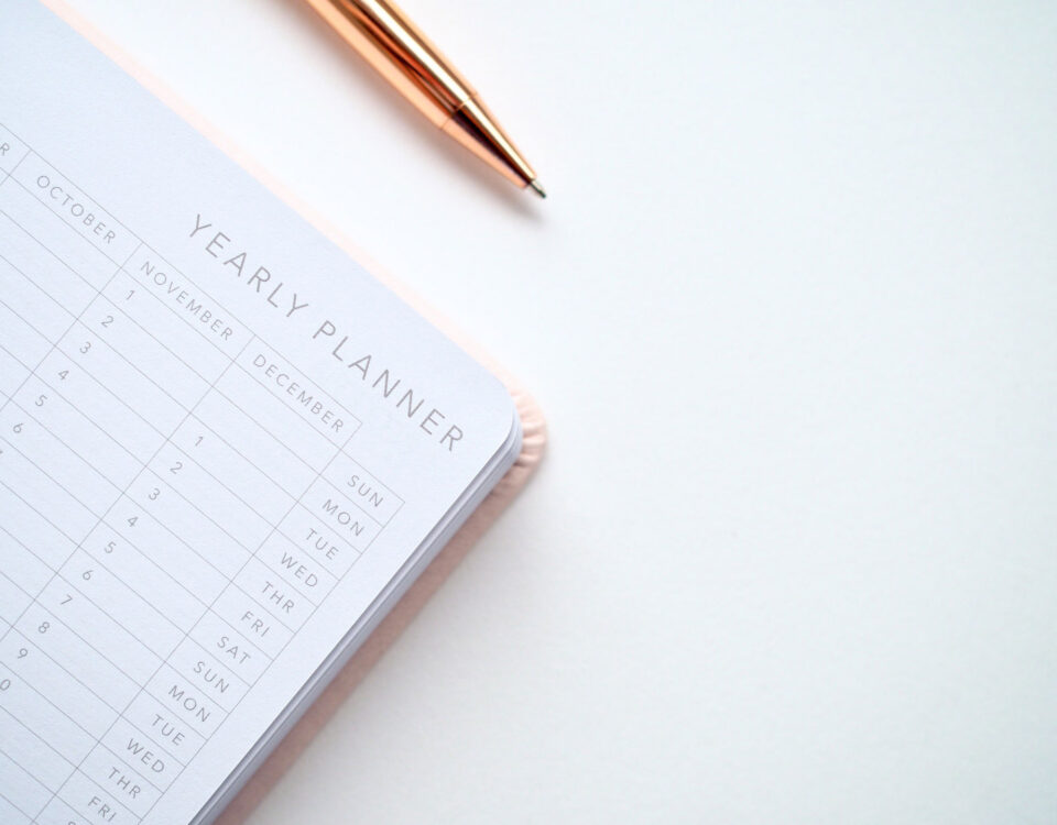 Yearly planner book sitting on a white table with a pen.